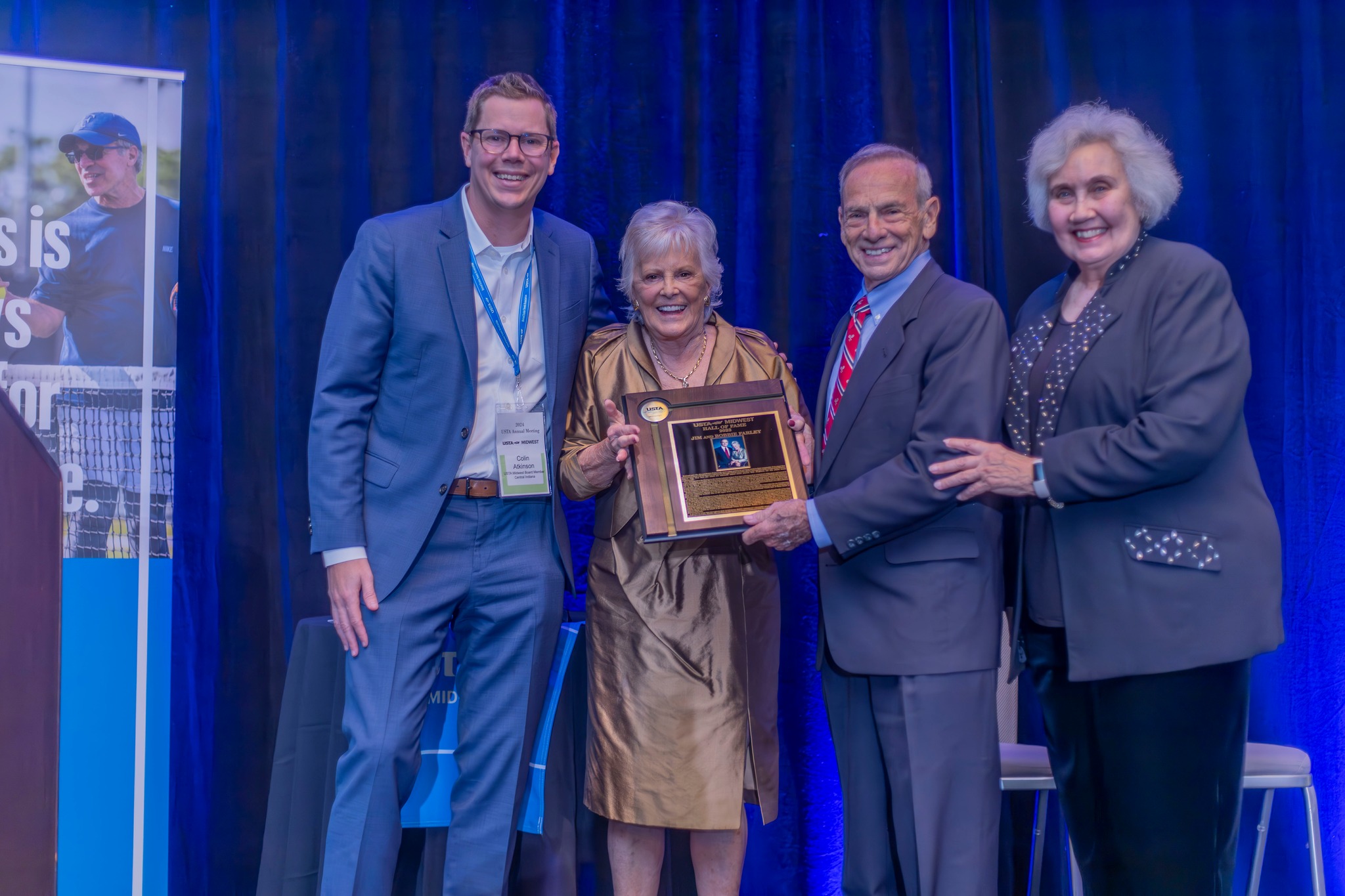 Bobbie and Jim Farley posing with their USTA Midwest Hall of Fame plaque in between USTA Midwest President, Colin Atkinson (left) and USTA Midwest Hall of Fame Chair, Jonelle Smith (right).